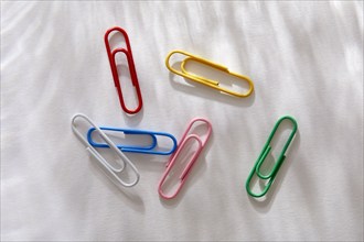 Overhead view of colorful paper clips on white background, New York, NY, USA