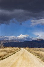 Empty dirt road leading to foothills under stormy skies, Fairfield, Idaho, USA