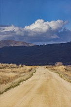 Empty dirt road leading to foothills under stormy skies, Fairfield, Idaho, USA