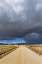 Storm clouds over empty dirt road in rural landscape, Fairfield, Idaho, USA