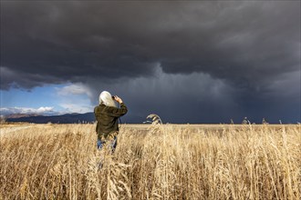 Rear view of woman taking photo of approaching storm with smart phone, Fairfield, Idaho, USA