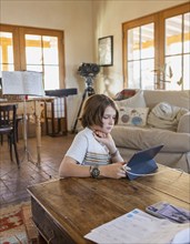 Boy looking at digital tablet at table in living room, Lamy, New Mexico, USA