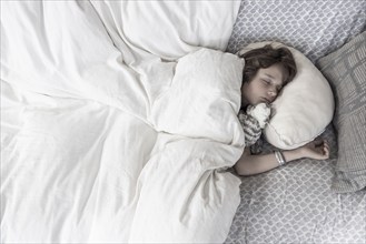 Overhead view of boy sleeping with stuffed toy in bed, Lamy, New Mexico, USA