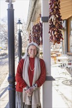 Portrait of smiling woman leaning against column at sidewalk cafe, Lamy, New Mexico, USA