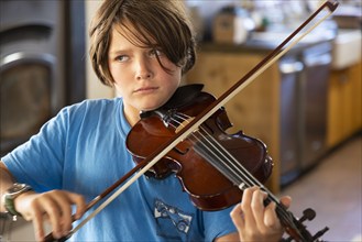 Boy playing violin at home, Lamy, New Mexico, USA