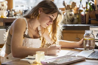 Teenage girl painting with watercolors at table, Lamy, New Mexico, USA