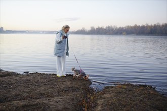 Woman with Yorkshire Terrier on lakeshore, Omsk, , Russia