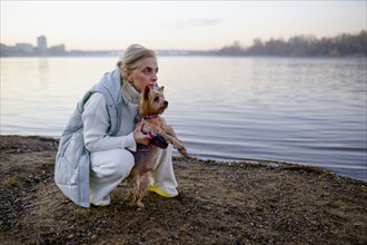 Woman with Yorkshire Terrier on lakeshore, Omsk, , Russia