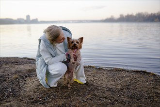 Woman with Yorkshire Terrier on lakeshore, Omsk, , Russia