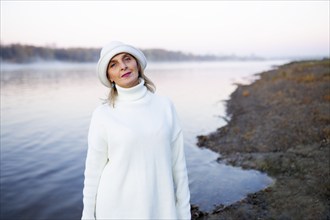 Portrait of woman in white hat and sweater on lakeshore, Omsk, , Russia