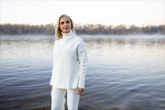 Portrait of woman in white sweater on lakeshore, Omsk, , Russia