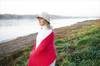 Portrait of woman wrapped in red shawl on lakeshore, Omsk, , Russia