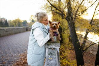 Woman with Yorkshire Terrier by river in autumn, Omsk, , Russia