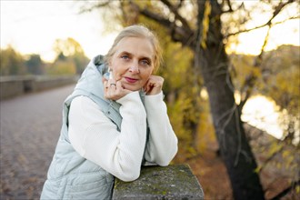 Portrait of woman leaning on wall by river in autumn, Omsk, , Russia