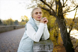 Portrait of woman leaning on wall by river in autumn, Omsk, , Russia