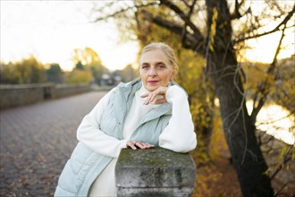 Portrait of woman leaning on wall by river in autumn, Omsk, , Russia