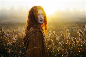 Portrait of redhead women in foggy field in autumn, Omsk, , Russia