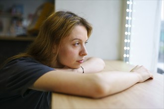 Woman leaning on window sill and looking through window, Omsk, , Russia