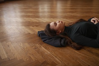 Pensive woman lying on parquet floor, Novosibirsk, , Russia