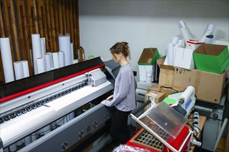 Woman operating machine in printing studio, Omsk, , Russia