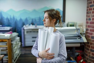 Woman holding rolled paper in printing studio, Omsk, , Russia