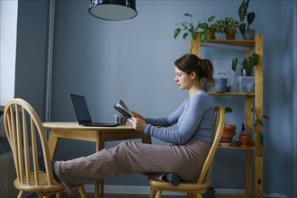 Woman reading at table at home, Omsk, , Russia