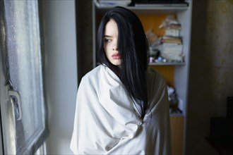 Portrait of pensive woman wrapped in white sheet, Omsk, , Russia