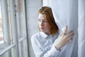 Portrait of pensive woman looking through window, Omsk, , Russia