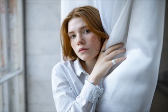 Portrait of pensive woman standing by window, Omsk, , Russia