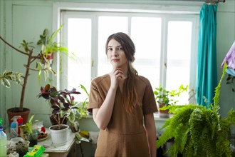 Portrait of pensive woman surrounded with plants against window, Omsk, , Russia