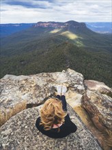 Overhead view of woman sitting on top on mountain, looking at view, Katoomba, New South Wales,