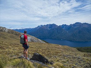 Hiker looking at fjord and mountains in Fiordland National Park, Te Anau, Fiordland, New Zealand