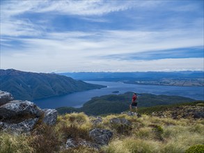 Hiker looking at fjord and mountains in Fiordland National Park, Te Anau, Fiordland, New Zealand