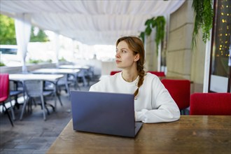 Pensive woman with laptop at cafe table, Omsk, , Russia