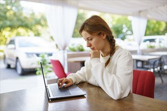 Woman using laptop at cafe table, Omsk, , Russia