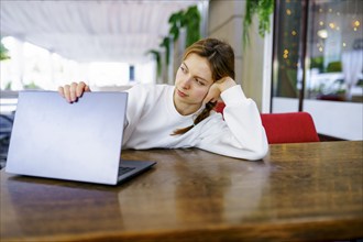 Woman looking at laptop at cafe table, Omsk, , Russia