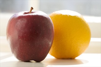 Apple and orange on table in sunlight, Chatham, New Jersey, USA