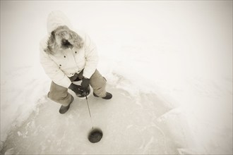 USA, NY, Hammond, High angle view of man ice fishing on frozen Black Lake, Hammond, Hammond, New