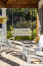 Rocking chair and swing on front porch of cottage house, Mt. Horeb, Wisconsin, USA