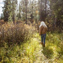 Rear view of woman walking through forest, Sun Valley, Idaho, USA