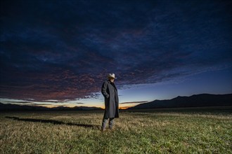 USA, Idaho, Bellevue, Rancher in overcoat standing in field at sunrise, Bellevue, Idaho, USA