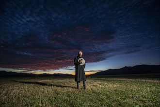 USA, Idaho, Bellevue, Rancher in overcoat standing in field, holding hat over heart, Bellevue,