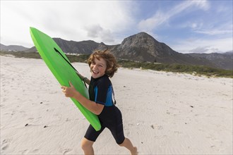 South Africa, Hermanus, Smiling boy running on beach with body board, Hermanus, , South Africa