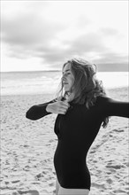 South Africa, Hermanus, Teenage girl putting on wetsuit on beach, Hermanus, , South Africa