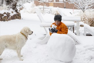 Boy with his dog building snowman, Santa Fe, New Mexico, USA