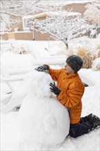 Boy building snowman, Santa Fe, New Mexico, USA