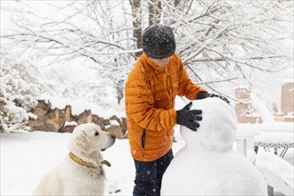 Boy with his dog building snowman, Santa Fe, New Mexico, USA