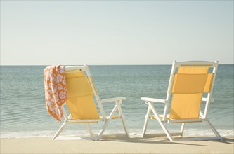 USA, Massachusetts, Nantucket, Two yellow beach chairs on sandy beach facing ocean, Nantucket,