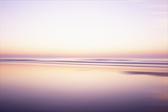 USA, New Jersey, Stone Harbor, Calm purple and orange water surface and sky at sunrise, Stone