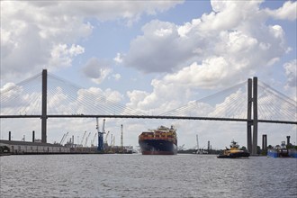 Cargo ship and tugboat under bridge at dock, Savannah, Georgia, USA